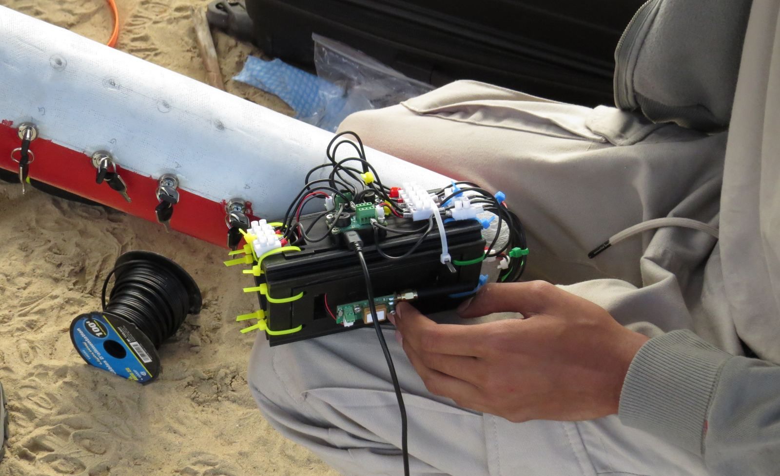 An avionics sled held next to Pioneer's red airframe on the sand