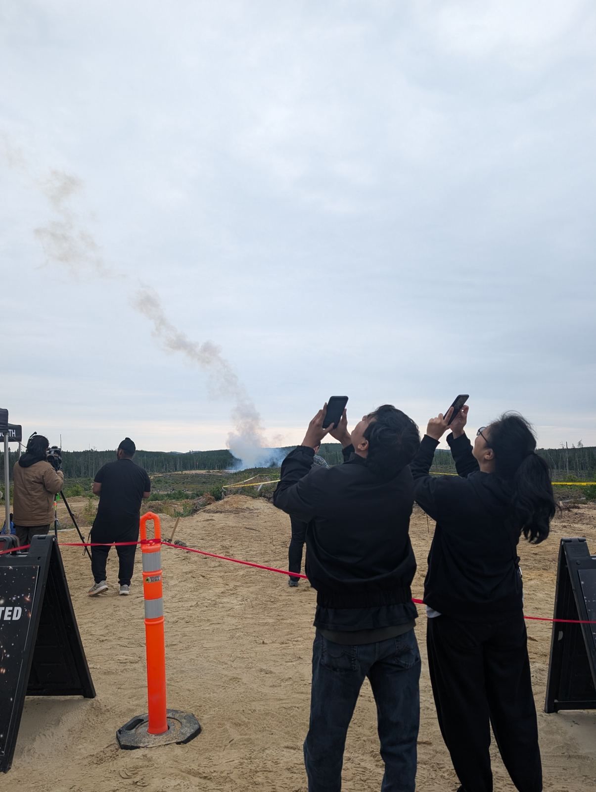 Two team members photographing another team's launch from the flight line