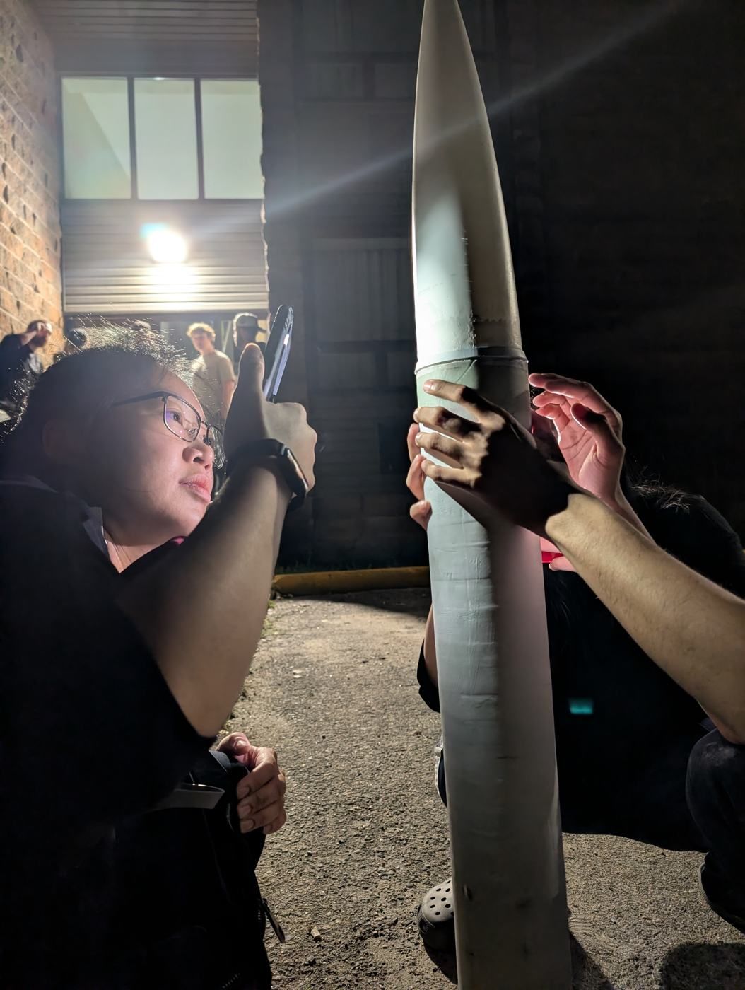 A member at night photographing a rocket held upright